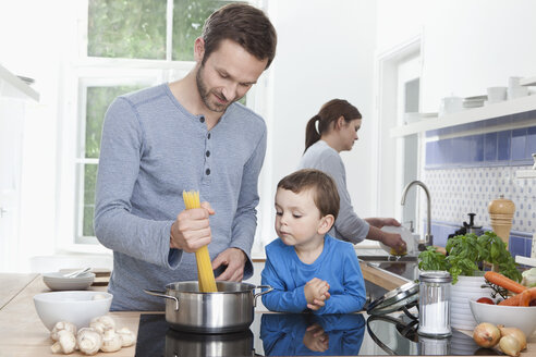 Deutschland, Bayern, München, Vater und Sohn (2-3 Jahre) kochen Spaghetti, Mutter im Hintergrund - RBF000365