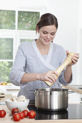 Deutschland, Bayern, München, Frau bereitet Essen in der Küche vor, lächelnd - RBF000370