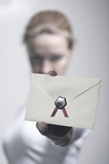 Deutschland, Vechelde, Frau zeigt versiegelten Umschlag - HKF000344