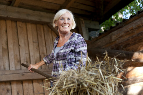 Deutschland, Sachsen, Ältere Frau bei der Arbeit auf dem Bauernhof, lächelnd - MBF001054