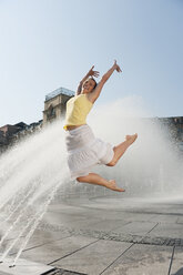 Germany, Munich, Karlsplatz, Young woman jumping in the air - RNF000432