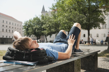 Germany, Munich, Karlsplatz, Young man resting on bench in university - RNF000402