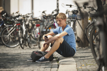 Deutschland, München, Karlsplatz, Junger Mann mit Handy in der Universität - RNF000400