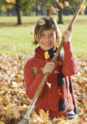 Germany, Nuremberg, Girl with rake in leaves, smiling, portrait - WBF000466