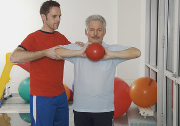 Deutschland, Nürnberg, Fitnesstrainer beim Training eines älteren Mannes - WBF000471