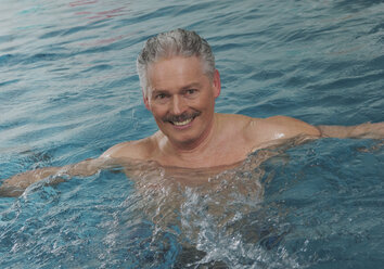 Germany, Nuremberg, Senior man in swimming pool, portrait, smiling - WBF000472