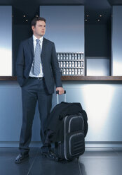 Germany, Ingolstadt, Business man with luggage waiting in lobby - WBF000555