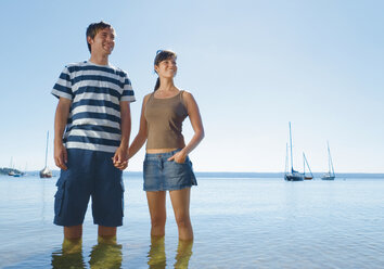 Germany, Ammersee, Young couple standing in lake, smiling - WBF000565