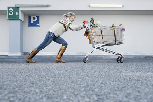 Germany, Young woman pushing shopping cart - WBF000601