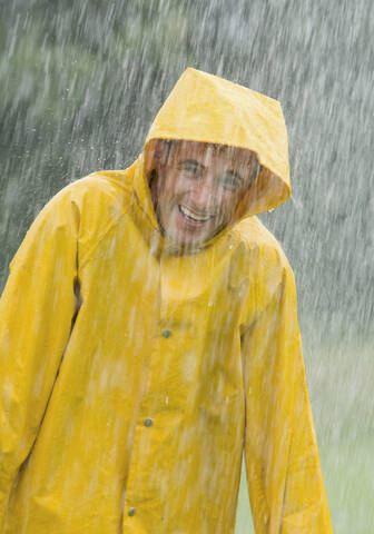 Man wearing rain coat standing in rain, portrait stock photo