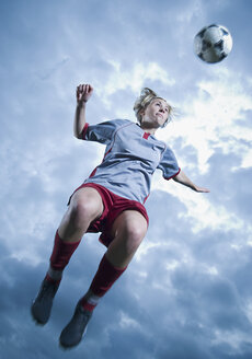 Deutschland, Augsburg, Fußballspieler springt in die Luft, um einen Ball zu köpfen - WBF000790