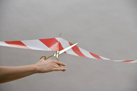 Germany, Vechelde, Hand of woman cutting a ribbon barrier stock photo