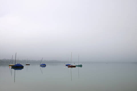 Deutschland, Bayern, Wörthsee, Blick auf Boote im See bei Morgennebel, lizenzfreies Stockfoto