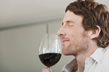 Germany, Hamburg, Man tasting the wine in kitchen - WESTF015564