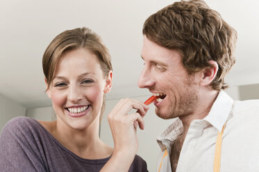 Germany, Hamburg, Woman feeding slice of capsicum to man - WESTF015581