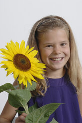 Mädchen (10-11 Jahre) hält Sonnenblume, lächelnd, Porträt - CRF001932