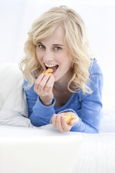 Germany, Leipzig, Young woman eating and smiling, portrait - MBF001144