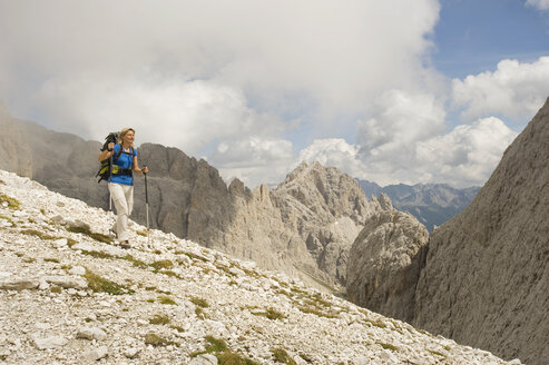 Italien, Dolomiten, Ältere Frau beim Wandern im Rosengarten - RNF000549