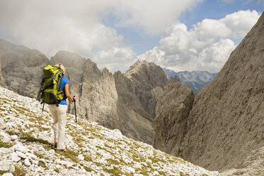 Italien, Dolomiten, Ältere Frau beim Wandern im Rosengarten - RNF000550