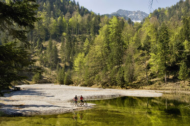 Germany, Bavaria, Garmisch, Mountain biker standing by lake - RNF000568