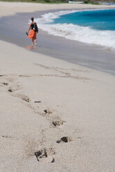 Asien, Indonesien, Lombok, Ältere Frau läuft am Sandstrand - GNF001188