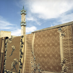 Jordanien, Amman, Traditionelle Teppiche mit Minarett im Hintergrund - PMF000821