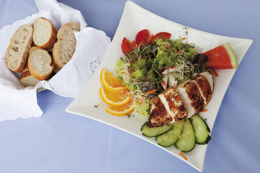 Close up of roasted chicken breast with mixed salad and friuts in square plate - CSF013700