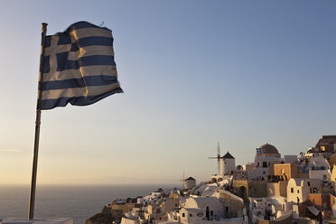 Griechische Flagge weht am Meer gegen Stadt und klaren Himmel, lizenzfreies  Stockfoto