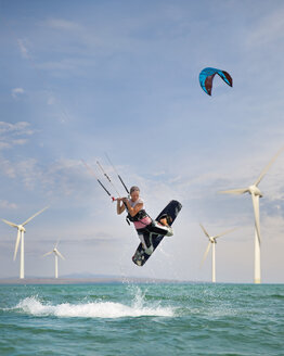 Croatia, Zadar, Kitesurfer jumping in front of wind turbine - HSIF000061