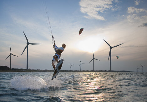 Kroatien, Zadar, Kitesurfer springt vor einer Windkraftanlage - HSIF000060
