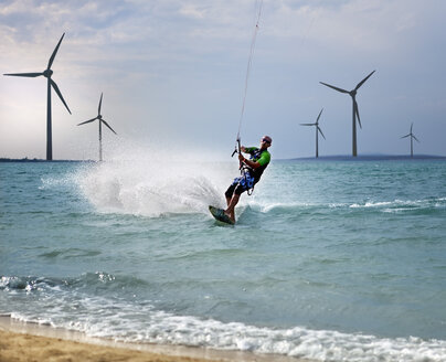 Kroatien, Zadar, Kitesurfer springt vor einer Windkraftanlage - HSIF000055