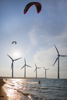 Kroatien, Zadar, Kitesurfer springen bei Sonnenuntergang vor einem Windrad - HSIF000058