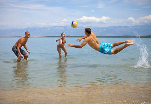 Kroatien, Zadar, Freunde spielen Volleyball am Strand, lizenzfreies Stockfoto
