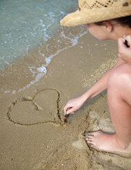 Croatia, Zadar, Young woman drawing heart-shaped on sand at beach - HSIF000044