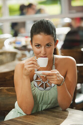 Germany, Munich, Young woman drinking coffee in cafe, smiling, portrait - RNF000513