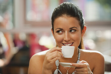 Germany, Munich, Young woman drinking coffee in cafe, smiling, portrait - RNF000511