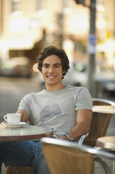 Germany, Munich, Young man in cafe, smiling, portrait - RNF000479
