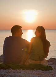 Croatia, Zadar, Young couple sitting near sea at sunset - HSIF000077
