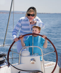 Croatia, Zadar, Mother and son steering wheel on sail boat - HSIF000088