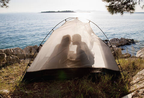 Kroatien, Zadar, Junges Paar küsst sich im Zelt am Strand, lizenzfreies Stockfoto
