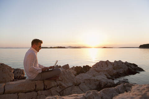 Kroatien, Zadar, Junger Mann mit Laptop am Strand, lizenzfreies Stockfoto