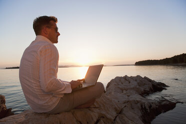 Kroatien, Zadar, Junger Mann mit Laptop am Strand - HSIF000101