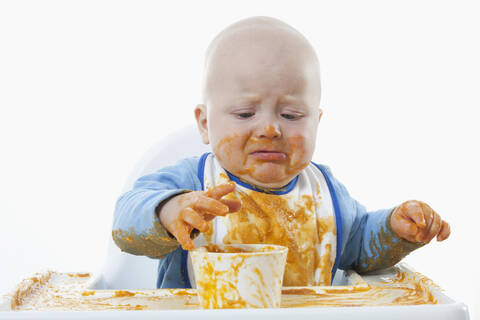Kleiner Junge (6-11 Monate) mit Babynahrung und Weinen, lizenzfreies Stockfoto