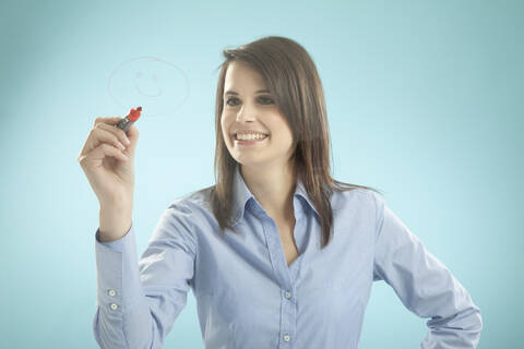 Geschäftsfrau, die lächelnd auf ein Brett zeichnet, lizenzfreies Stockfoto