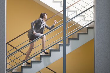 Germany, Bavaria, Business woman climbing stairscase - MAEF002757