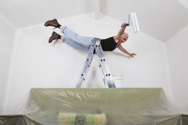 Germany, Cologne, Mature woman screaming while falling from ladder during painting gable roof - GWF001360