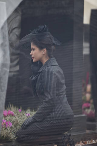 Deutschland, Bayern, Junge Frau beim Besuch eines Grabsteins auf dem Friedhof, lizenzfreies Stockfoto