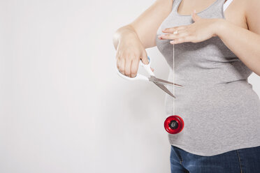 Germany, Cologne, Young woman cutting yo-yo string - PDF000080