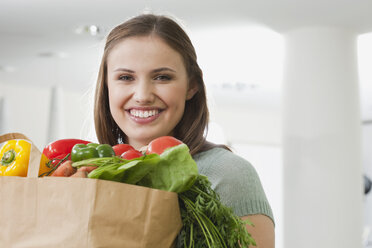 Deutschland, Köln, Junge Frau mit Tasche voller Gemüse, lächelnd, Porträt - PDF000105