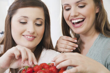 Germany, Cologne, Young women sharing strawberry, smiling - PDF000136